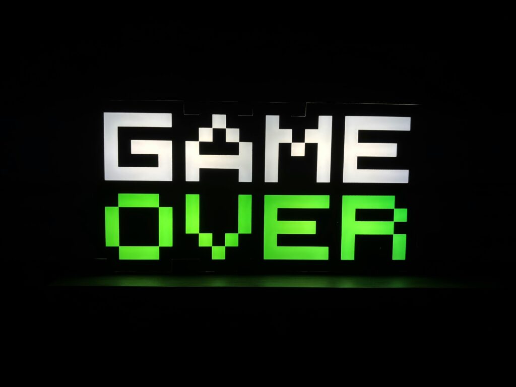 Illuminated 'Game Over' sign in pixel art style with neon green and white colors on a dark background.
